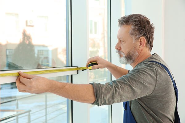 Service man measuring window for installation indoors